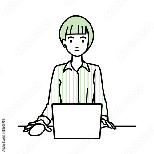 デスクで座ってPCを使っているブラウスの女性