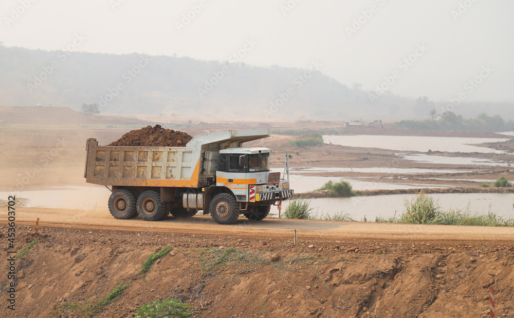 Obraz premium Closeup of dump-truck running on temporary road at dam construction site.