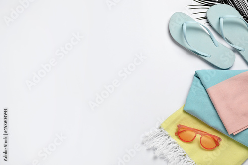 Beach towel, flip flops and sunglasses on white background, flat lay. Space for text