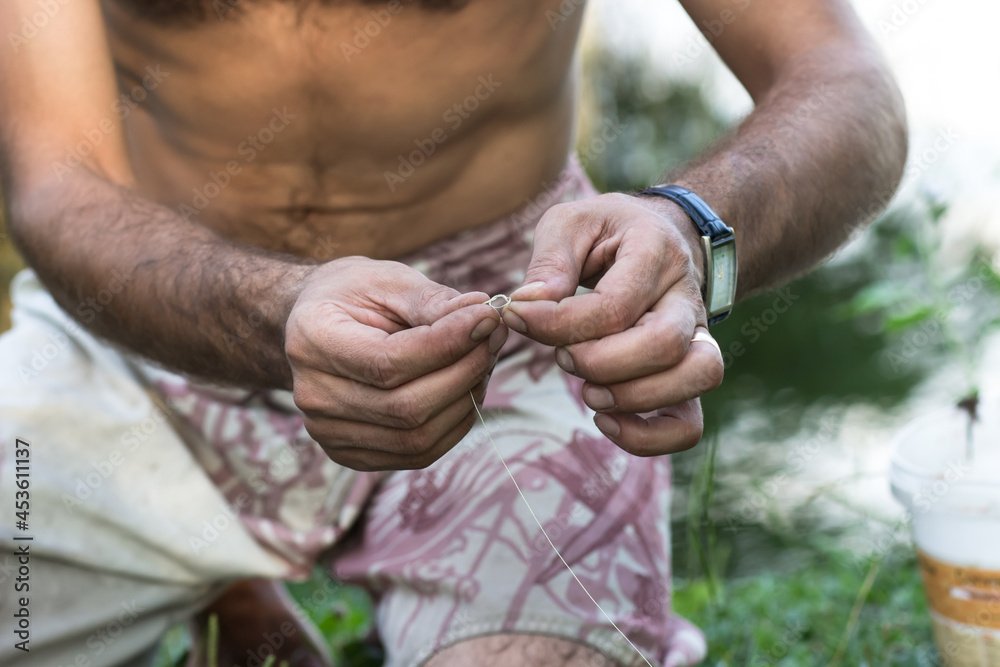 Hands of a young man who makes fishing gear