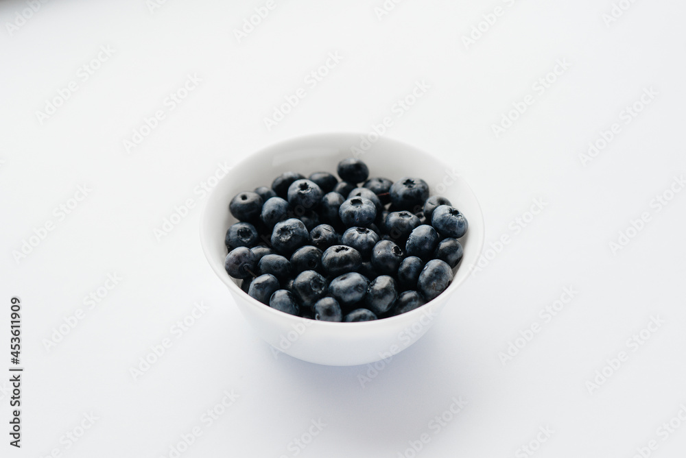 Beautiful ripe blueberries in a glass bowl on a white background. Healthy food, and vitamins. Beautiful ripe blueberries in a glass bowl on a white background. Healthy food, and vitamins.