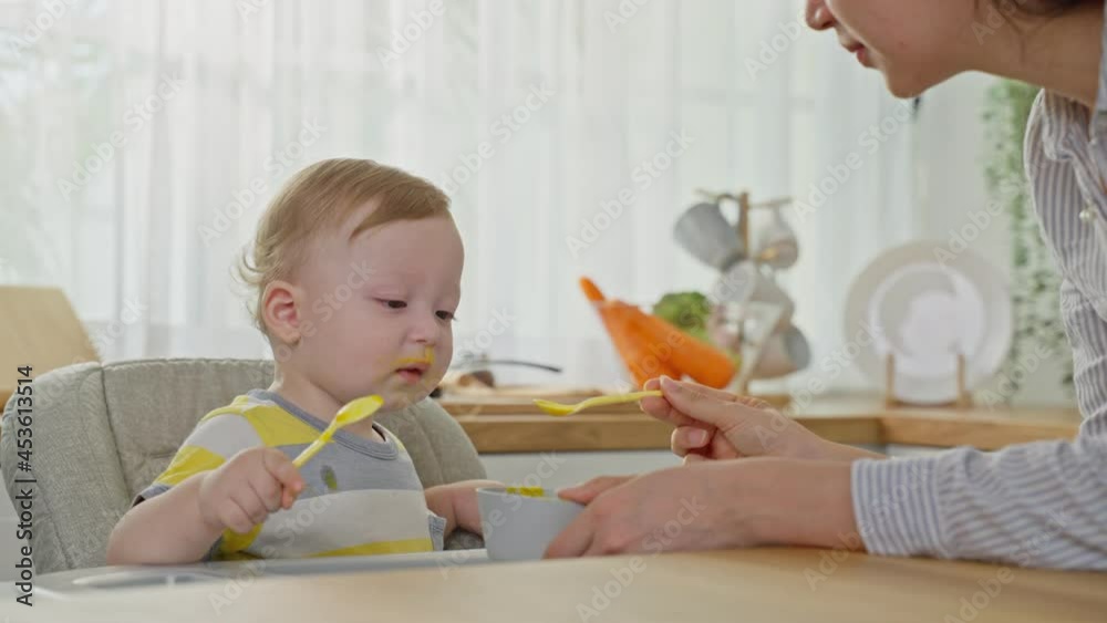 Caucasian attractive parents feeding foods to baby toddler in kitchen.