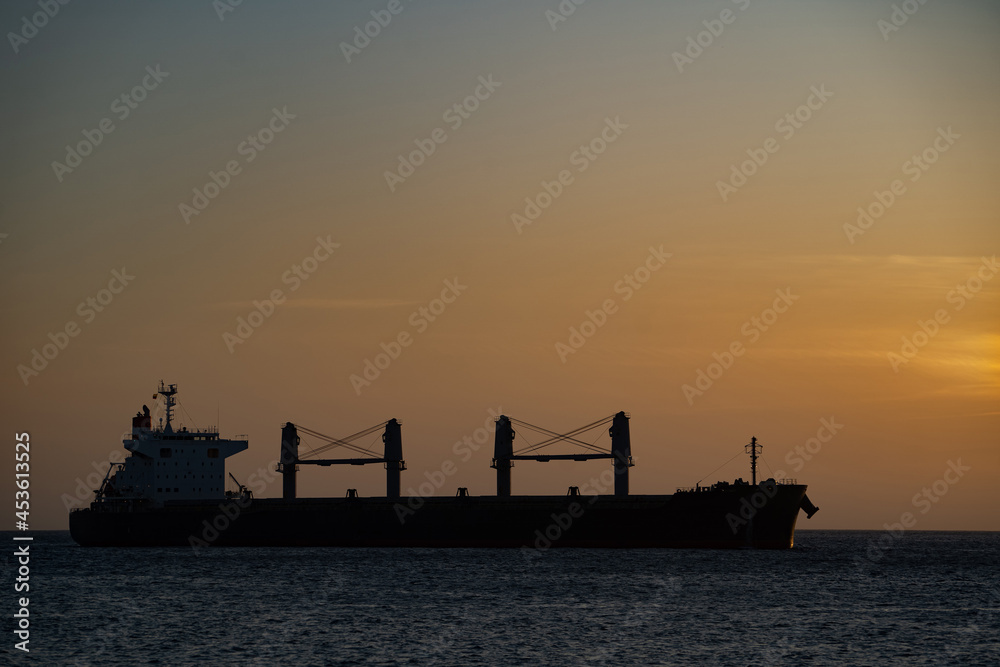 Silhouette of Cargo Container Ship at Sea during sunset. Concept of logistics and transportation 