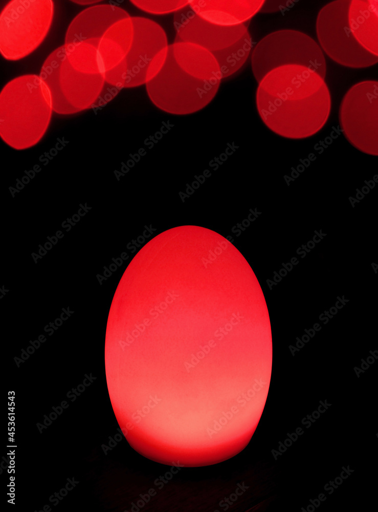 Shining Scarlet Red Egg Shaped Table Lamp with Bokeh Light on Dark Background Shining Scarlet Red Egg Shaped Table Lamp with Bokeh Light on Dark Background