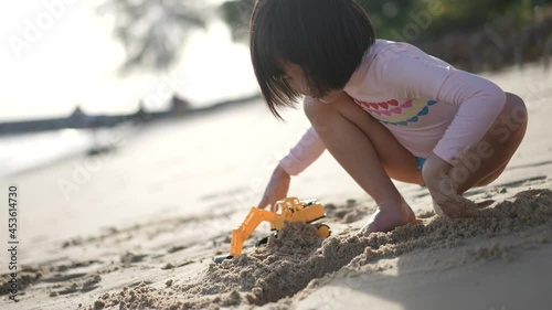 Slow motion of little asian chinese girl digging sand at the beach with her excavator outdoor sunny