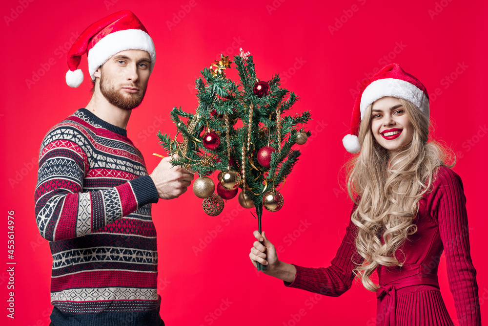 cheerful young couple in new year clothes decoration toys red background cheerful young couple in new year clothes decoration toys red background