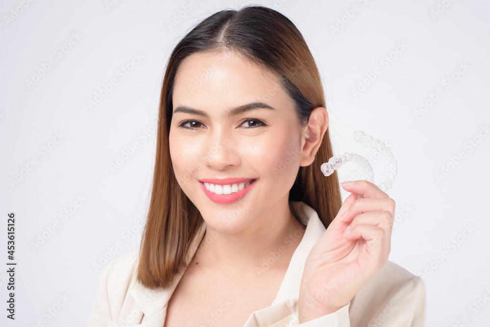Young smiling woman holding invisalign braces in studio, dental healthcare and Orthodontic concept Young smiling woman holding invisalign braces in studio, dental healthcare and Orthodontic concept