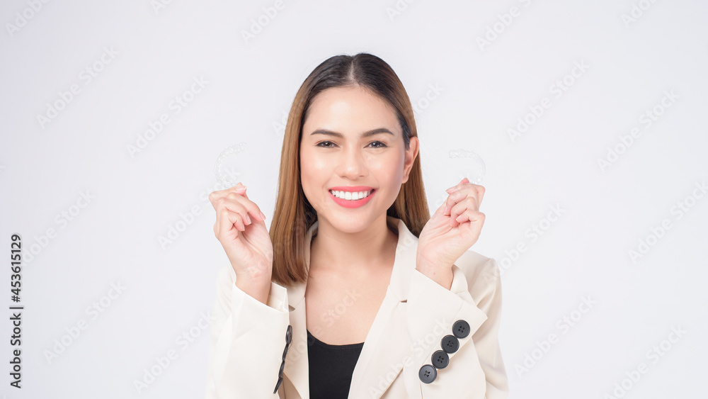 Young smiling woman holding invisalign braces in studio, dental healthcare and Orthodontic concept