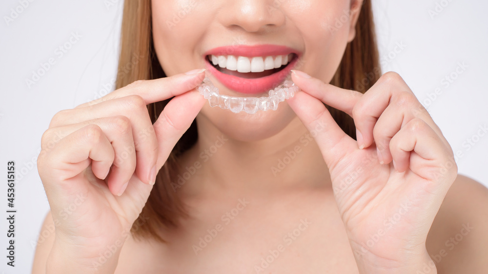 Young smiling woman holding invisalign braces in studio, dental healthcare and Orthodontic concept Young smiling woman holding invisalign braces in studio, dental healthcare and Orthodontic concept
