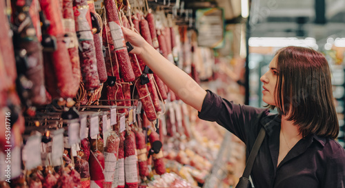 Young woman chooses salami sausage in a supermarket © pavel siamionov