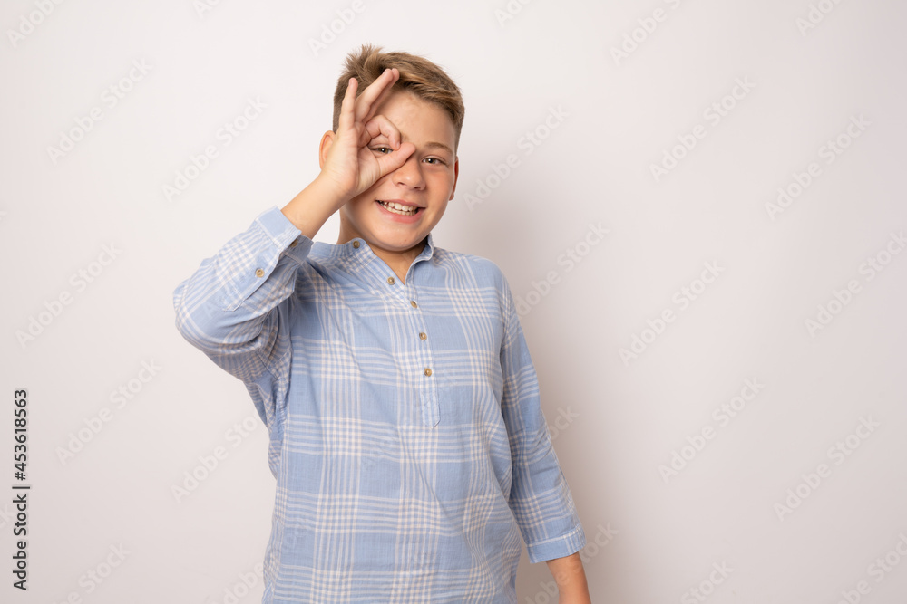 Portrait of handsome boy making okay Gesture with hand on eye looking through fingers Portrait of handsome boy making okay Gesture with hand on eye looking through fingers