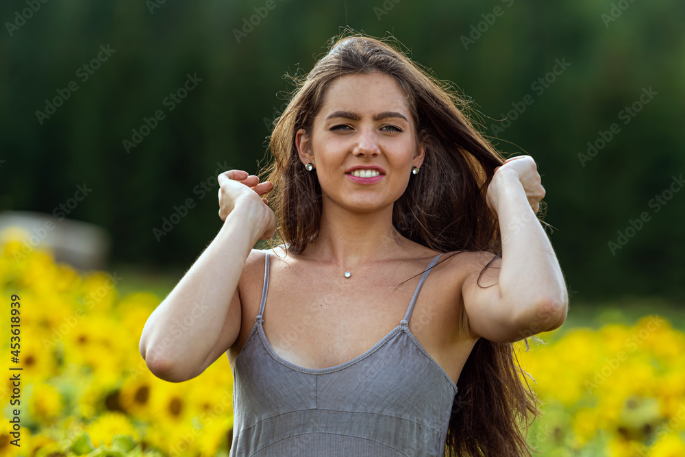 young woman with long hair in linean country style dress walks through a field of sunflowers young woman with long hair in linean country style dress walks through a field of sunflowers