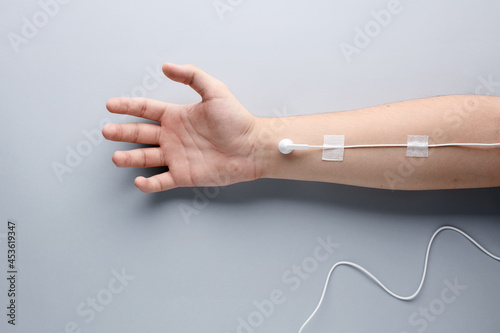 Male arm with earphone attached as medical serum. Music addiction or audiophile concept photo