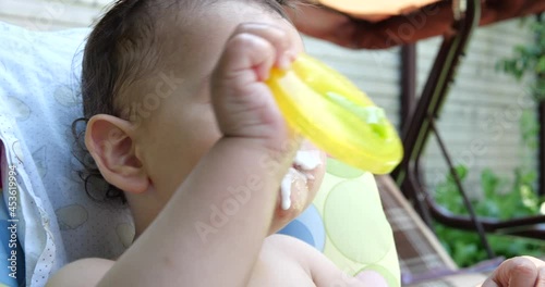 Portrait of a little boy who sits on a child's chair. Happy child drinks milk, kefir or dairy products from a cup. Correct and natural nutrition for children