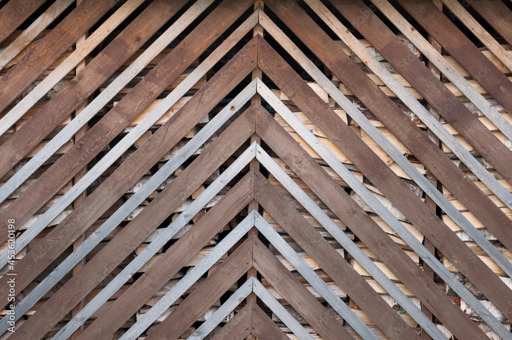 Openwork wooden wall of the shed for firewood from boards of different thicknesses Openwork wooden wall of the shed for firewood from boards of different thicknesses