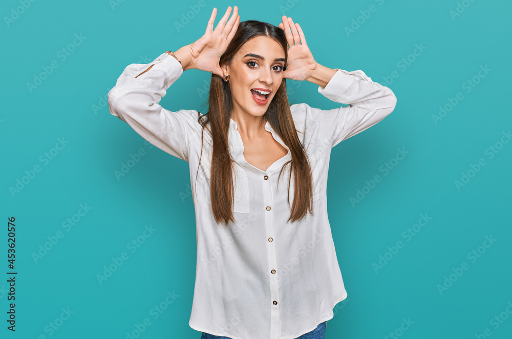 Young beautiful woman wearing casual white shirt smiling cheerful playing peek a boo with hands showing face. surprised and exited Young beautiful woman wearing casual white shirt smiling cheerful playing peek a boo with hands showing face. surprised and exited