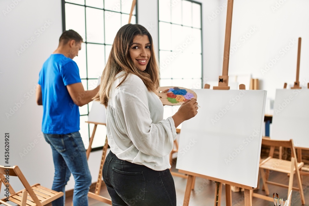 Two students smiling happy painting at art school. Two students smiling happy painting at art school.
