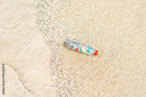 Top view of a bottle filled with microplastics collected from the sea on the shore of the beach.