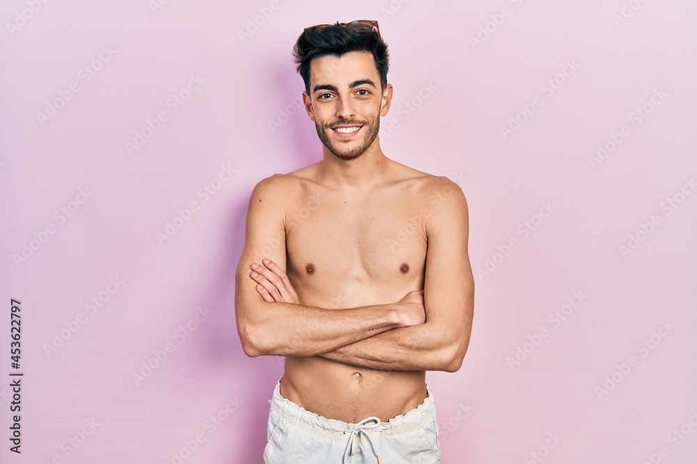 Fototapeta premium Young hispanic man wearing swimwear shirtless happy face smiling with crossed arms looking at the camera. positive person.
