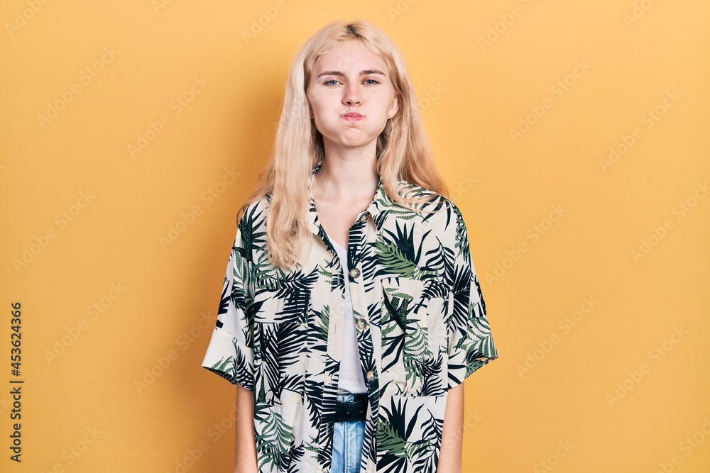 Beautiful caucasian woman with blond hair wearing tropical shirt puffing cheeks with funny face. mouth inflated with air, crazy expression. Beautiful caucasian woman with blond hair wearing tropical shirt puffing cheeks with funny face. mouth inflated with air, crazy expression.