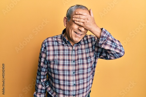 Handsome senior man with grey hair wearing casual shirt smiling and laughing with hand on face covering eyes for surprise. blind concept. © Krakenimages.com
