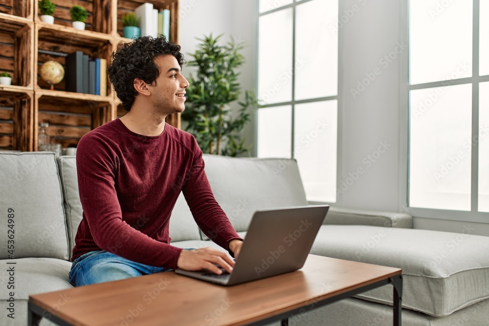 Young hispanic man using laptop sitting on the sofa at home. Young hispanic man using laptop sitting on the sofa at home.