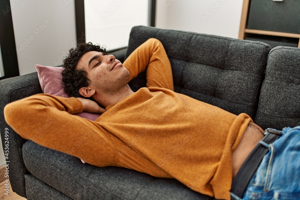 Young hispanic man smiling happy lying on the sofa at home. Young hispanic man smiling happy lying on the sofa at home.