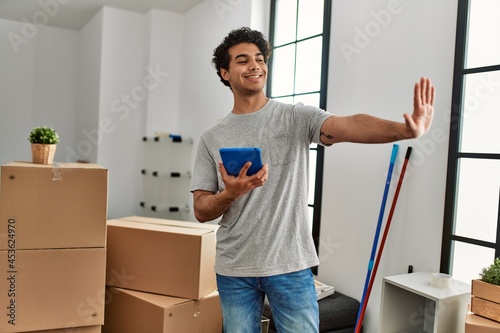 Young hispanic man using touchpad moving at new home.