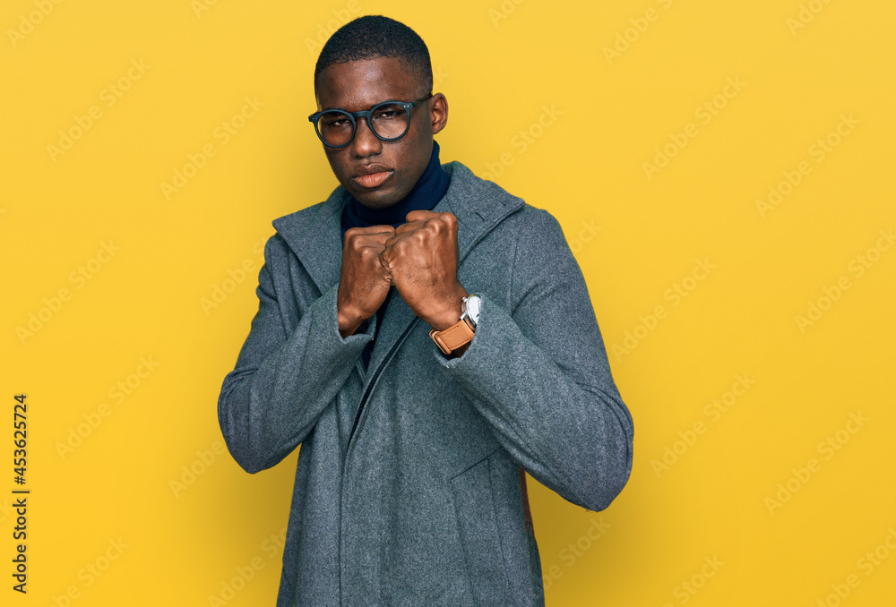 Young african american man wearing business clothes and glasses ready to fight with fist defense gesture, angry and upset face, afraid of problem Young african american man wearing business clothes and glasses ready to fight with fist defense gesture, angry and upset face, afraid of problem