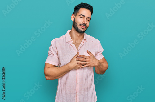 Hispanic man with beard wearing casual shirt smiling with hands on chest with closed eyes and grateful gesture on face. health concept.