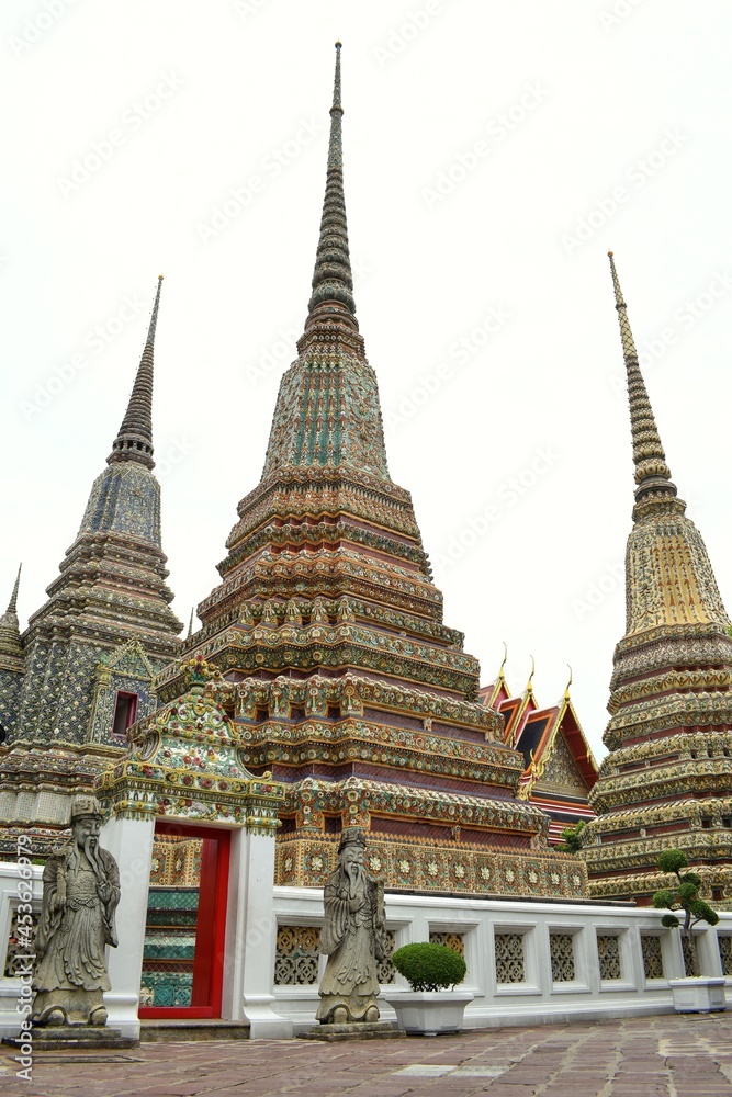 Fototapeta premium Phra Maha Chedi Si Rajakarn is a group of four large stupas and European stone figure at Wat Pho also spelled Wat Po, is a Buddhist temple in Bangkok, Thailand.
