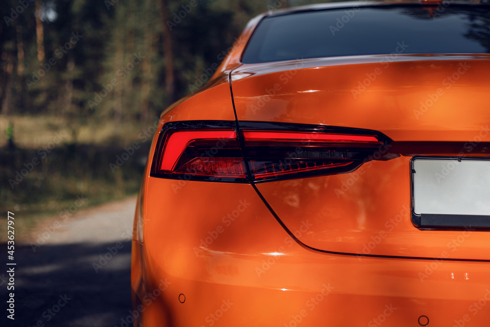 LED rear light. Detail on the rear light of a car. Modern orange color car. Car detail. Developed Car's rear brake light. Automotive concept