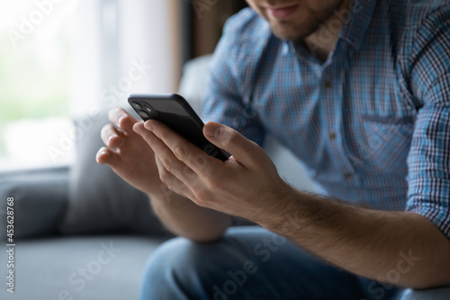 Hands of man using online virtual app on mobile phone. Millennial guy chatting on smartphone, using banking services, reading text message, typing, shopping, making call, browsing internet. Close up photo
