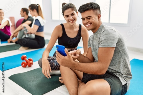 Group of young hispanic people smiling happy relaxing and using smartphone at sport center.