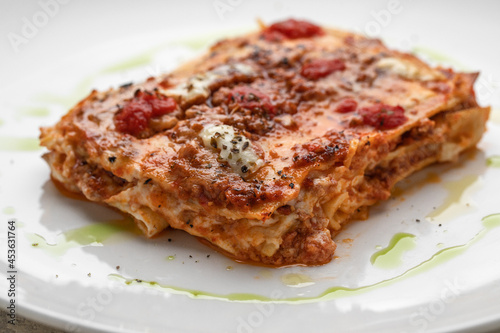 Take Out Creamy Lasagna with fresh mozzarella and tomatoes on white plate macro close up