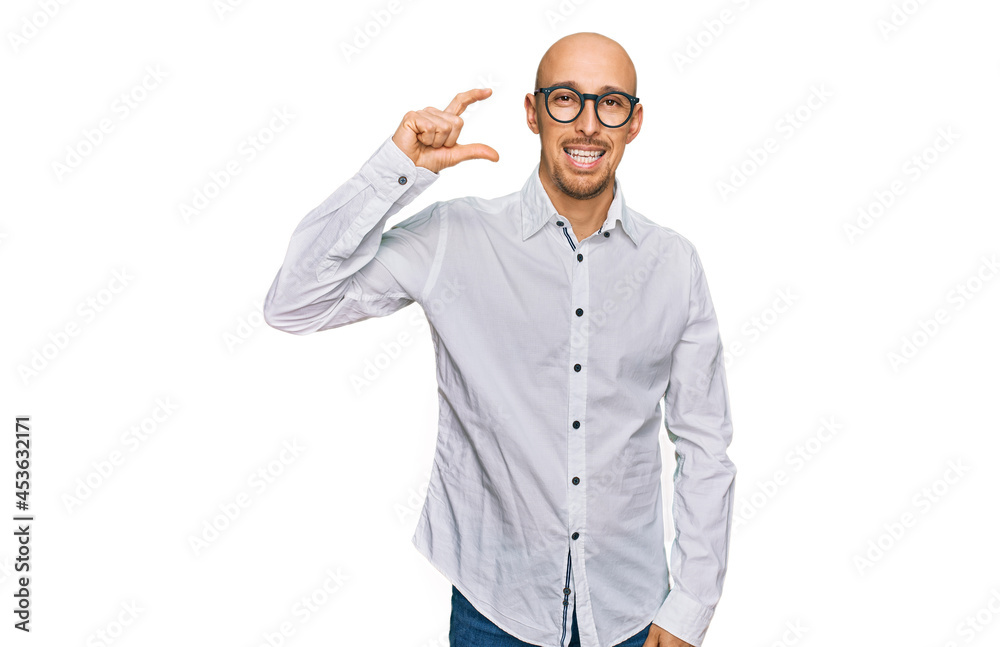 Bald man with beard wearing business shirt and glasses smiling and confident gesturing with hand doing small size sign with fingers looking and the camera. measure concept. Bald man with beard wearing business shirt and glasses smiling and confident gesturing with hand doing small size sign with fingers looking and the camera. measure concept.