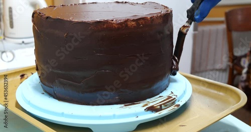Confectioner woman is smearing cream on sides of cake using spatula, closeup view. culinary, baking and cooking food concept, home cooking
