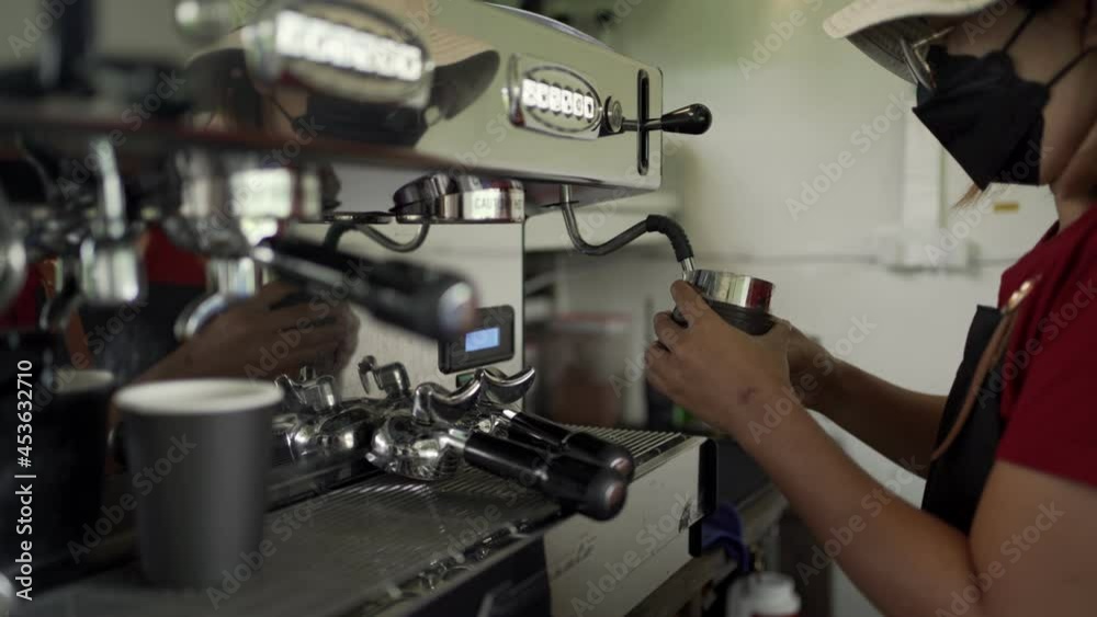 Coffee worker using a large coffee machine in a café.