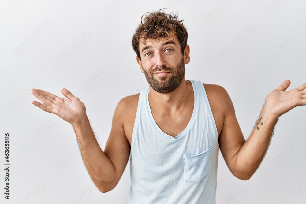 Young handsome man standing over isolated background clueless and confused expression with arms and hands raised. doubt concept. Young handsome man standing over isolated background clueless and confused expression with arms and hands raised. doubt concept.