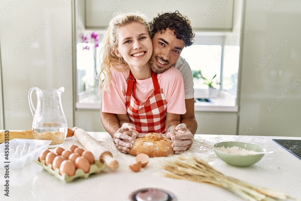 Young couple smiling happy cooking homemade bread at kitchen. Young couple smiling happy cooking homemade bread at kitchen.