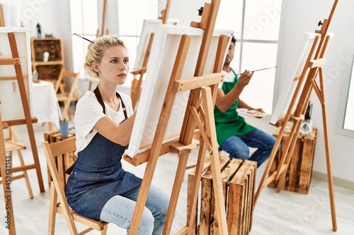 Young artist couple concentrated painting at art studio.