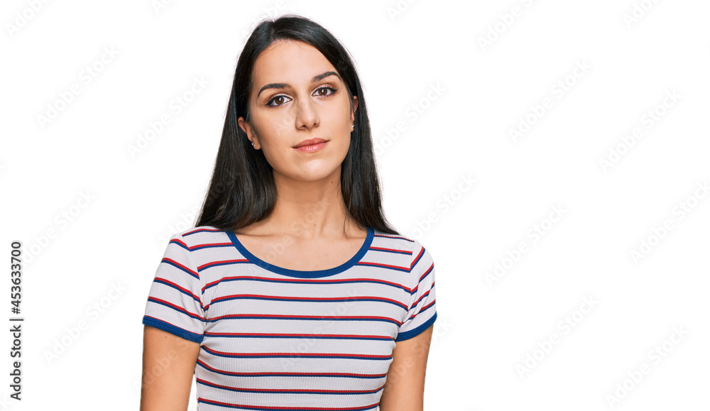 Young hispanic girl wearing casual striped t shirt relaxed with serious expression on face. simple and natural looking at the camera. Young hispanic girl wearing casual striped t shirt relaxed with serious expression on face. simple and natural looking at the camera.
