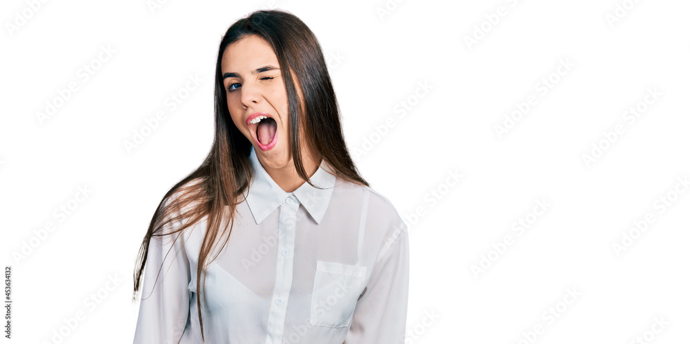 Young brunette teenager wearing business white shirt winking looking at the camera with sexy expression, cheerful and happy face. Young brunette teenager wearing business white shirt winking looking at the camera with sexy expression, cheerful and happy face.