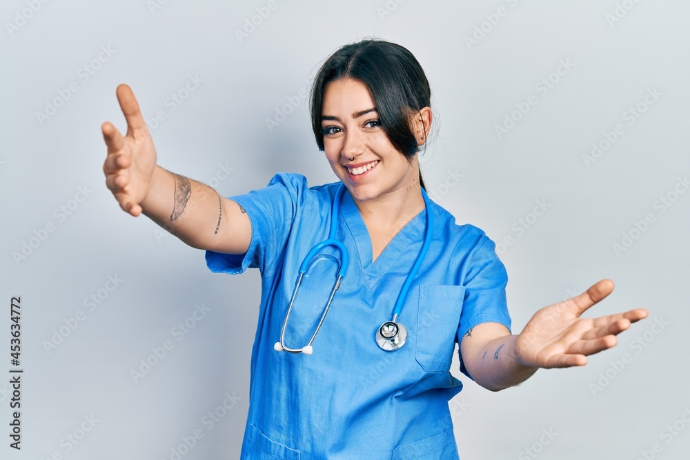 Beautiful hispanic woman wearing doctor uniform and stethoscope looking at the camera smiling with open arms for hug. cheerful expression embracing happiness. Beautiful hispanic woman wearing doctor uniform and stethoscope looking at the camera smiling with open arms for hug. cheerful expression embracing happiness.