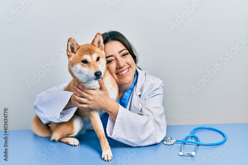 Fototapeta Naklejka Na Ścianę i Meble -  Veterinarian woman wearing uniform at the clinic, hugging dog with love