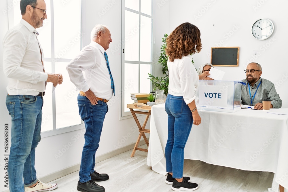 Group of middle age voter people putting vote in ballot standing at electoral center. Group of middle age voter people putting vote in ballot standing at electoral center.