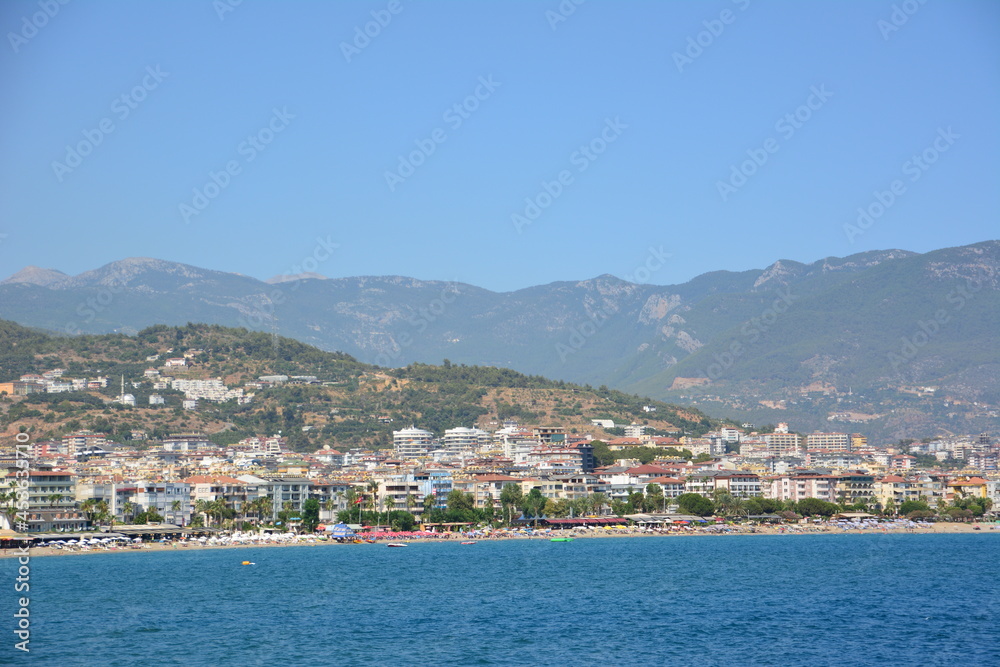 mediterranean town alanya with mountain and blue sky background, view from the sea to coastline