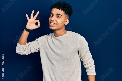 Young african american man wearing casual clothes smiling positive doing ok sign with hand and fingers. successful expression.