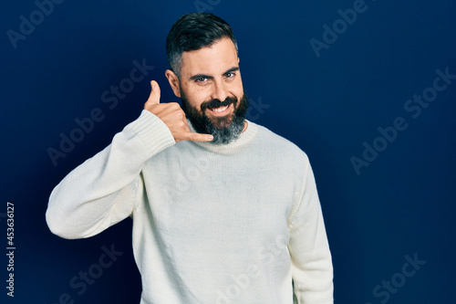 Young hispanic man wearing casual clothes smiling doing phone gesture with hand and fingers like talking on the telephone. communicating concepts.