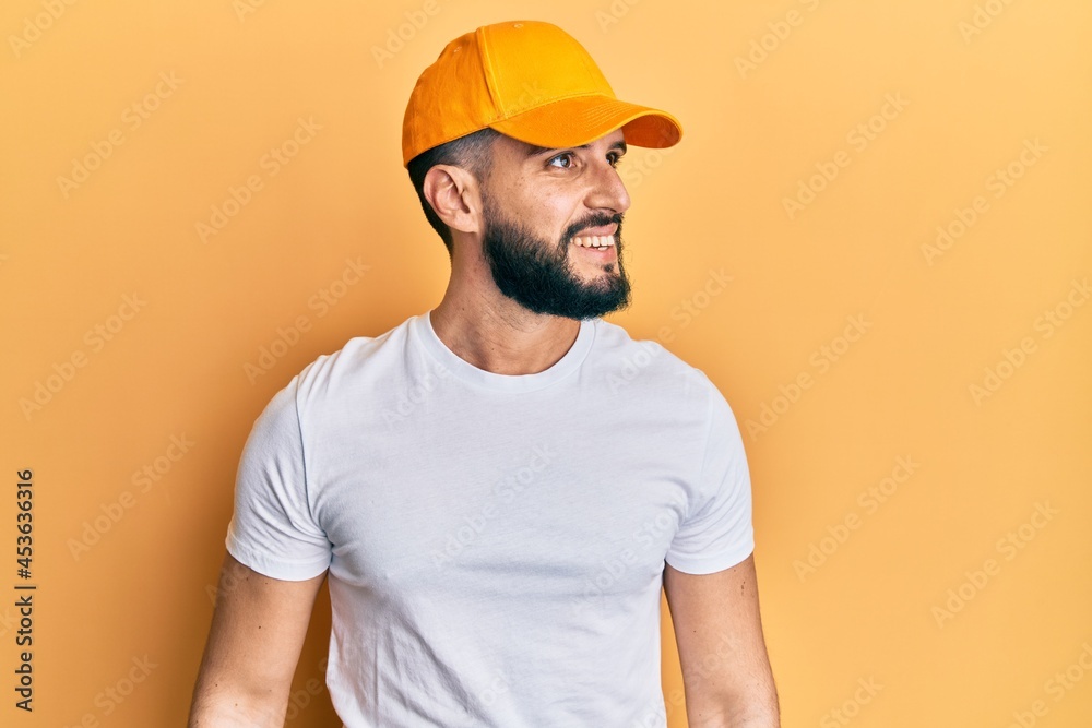 Young man with beard wearing yellow cap looking to side, relax profile pose with natural face and confident smile.
